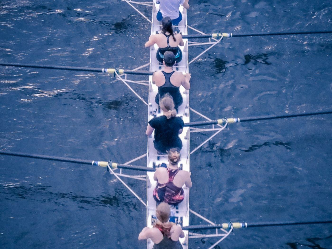 A rowing eight seen from above, every oar entering the water together.